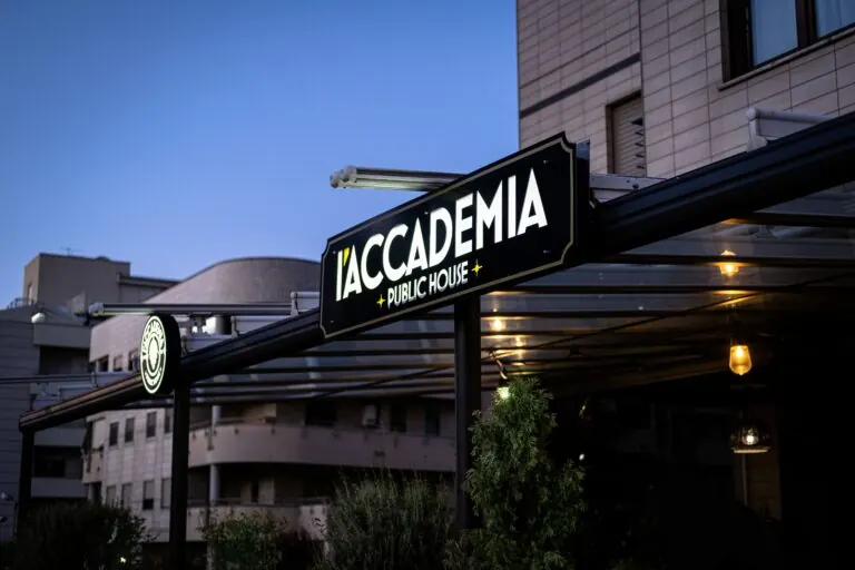 L’insegna e l’ingresso de L’Accademia Public House al tramonto