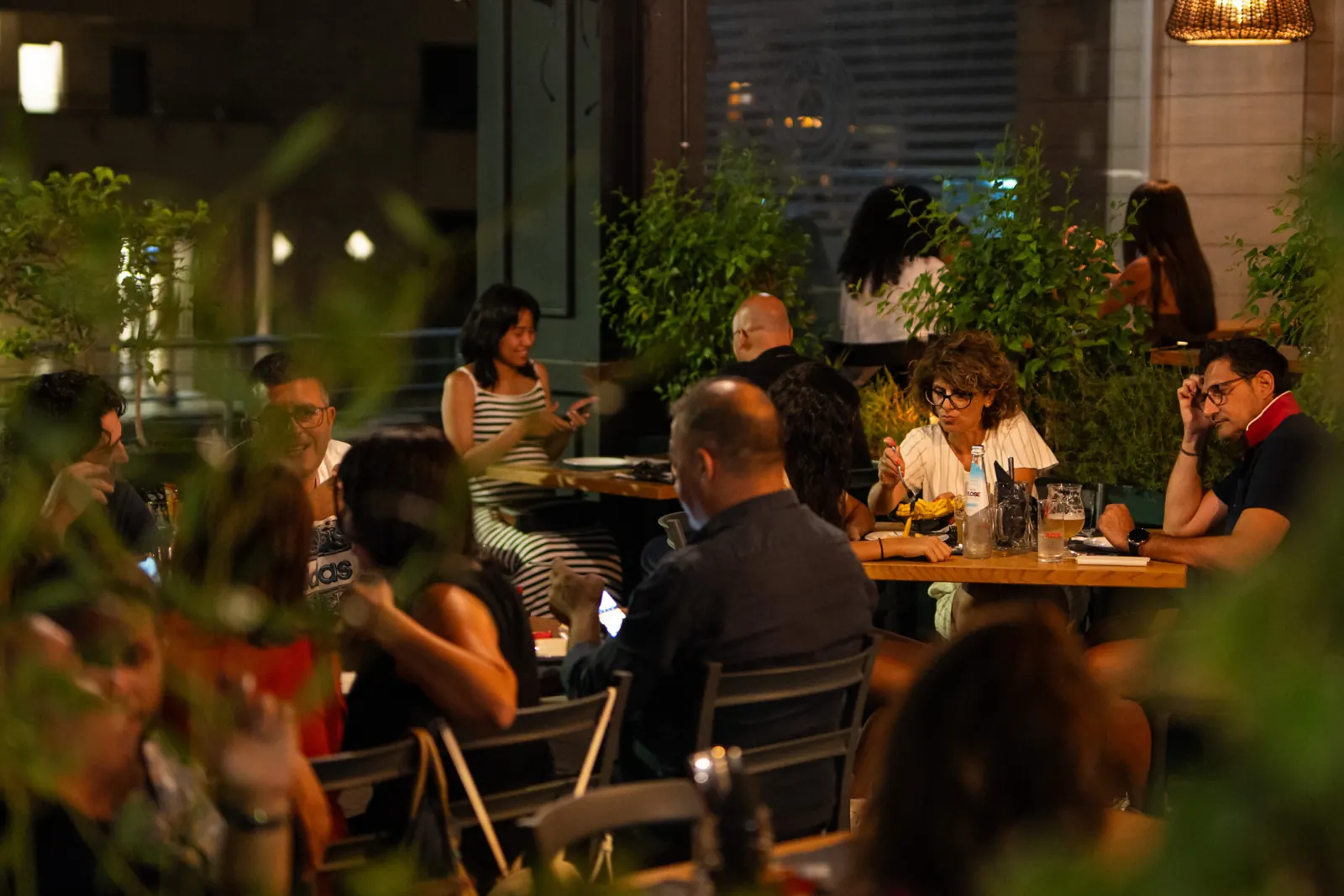 Una serata ai tavoli esterni de L’Accademia, tra piante e luci calde